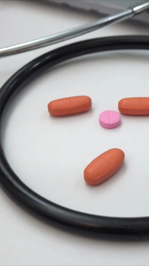 Person picking up a pill on a white surface with a stethoscope nearby Stock Footage 301943541