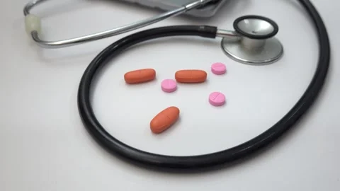 Person picking up a pill on a white surface with a stethoscope nearby Stock Footage 301943549