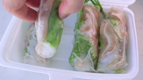 Person picking up vietnamese spring rolls from takeout container Video stock 337360305