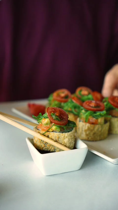 Person picks up a crispy sushi roll with chopsticks and dips it into soy sauce Stock Footage 346718656