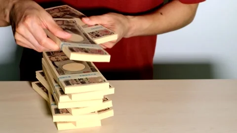 A person piling up stacks of cash Stockbeeldmateriaal 334828956