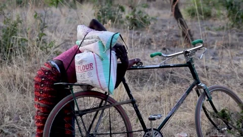 A person in a pink shirt and patterned skirt loading a heavy sack of flour onto Stock Footage 344910891