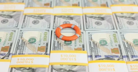 Person places a life preserver on a stack of hundred dollar bills Stock Footage 287553074
