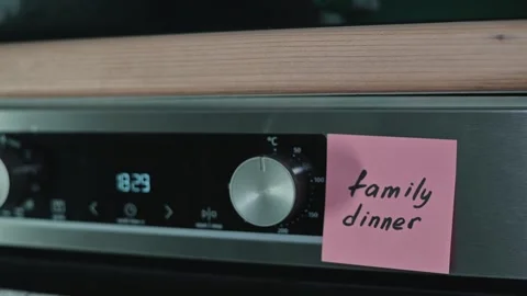 A person places a sticky note labeled family dinner on an oven display. This Stock Footage 339096759