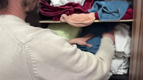 Person placing folded clothes into wardrobe shelf, home organization and storage Stock Footage 337110695