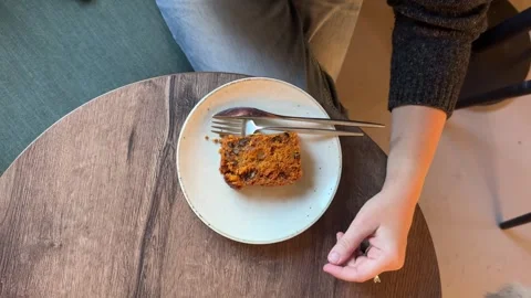 Person placing latte next to slice of cake on wooden table Stock Footage 337324990