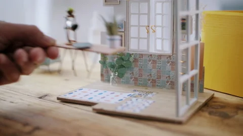 Person placing miniature table in model house Stock Footage 130323850