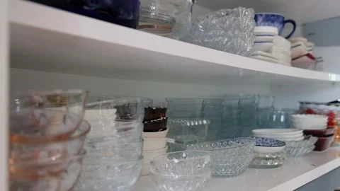 Person Placing Small Serving Plates Back into a Two-Shelf Kitchen Cabinet Stock Footage 302688173