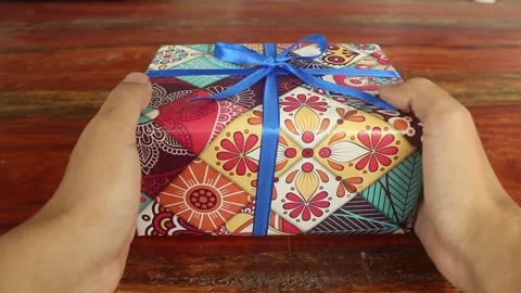 Person Placing Wrapped Gift in Center of Wooden Table Stock Footage 345293776