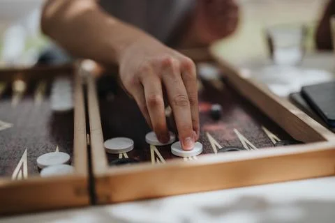 Person playing backgammon with focus on hand and game pieces Stock Photos