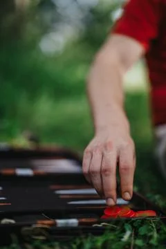 Person playing backgammon outdoors with focus on red game pieces Stock Photos