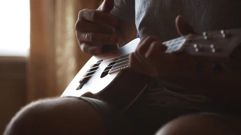 Person playing on ukulele guitar inside Stock Footage 79423935