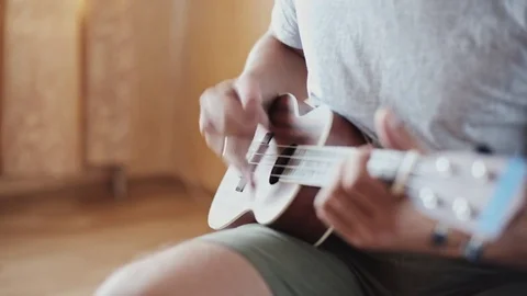 Person playing on ukulele guitar inside Stock Footage 80020458