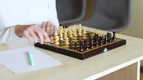 A person plays a game of chess at a table, moving a chess piece Stock Footage 278900126