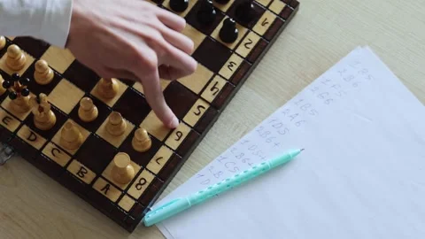 A person plays a game of chess while taking notes on a piece of paper Stock Footage 278900167