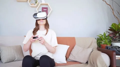 Person plays on the sofa in a virtual reality headset. Cozy light interior Stock Footage 148261337