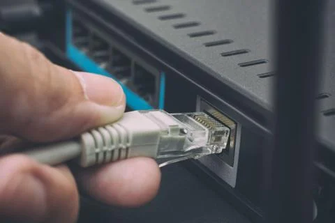 Person plugging in cable to wireless router Stock Photos