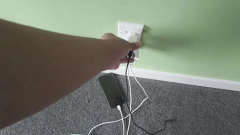 Person plugging a charger into wall socket Stock Footage 329574464