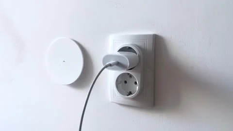 A person is plugging a device into a wall socket for electrical power and Stock Footage 283207952