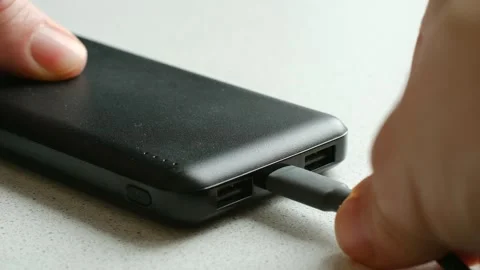 Person plugging usb c cable into a black power bank for charging Stock Footage 337828350