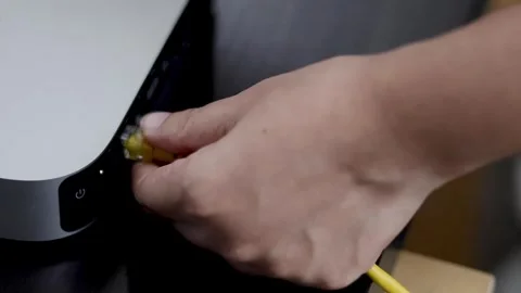 Person plugging yellow ethernet cable into port of silver mini computer on .. Stock Footage 333493229