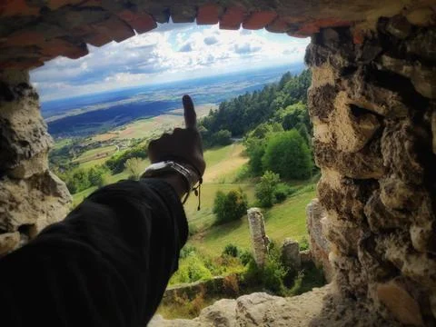Person Pointing Toward a Cloud Through an Ancient Stone Opening Foto stock