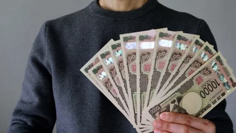 A person posing with a large number of 10,000 yen bills Stock Footage 324546870