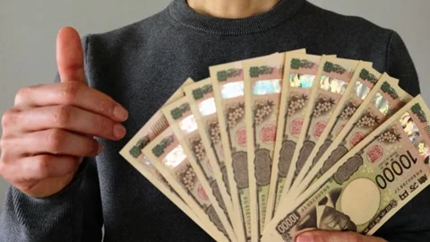 A person posing with a large number of 10,000 yen bills Stock Footage 324546871