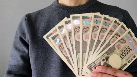 A person posing with a large number of 10,000 yen bills 動画素材 324547287