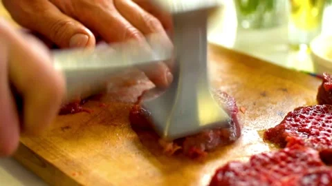 Person pounding raw beef meat with metal mallet tenderizer Stock Footage 333833841