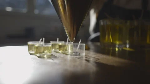 A person is pouring liquid into a container with a small candle in it Stock Footage 301794085