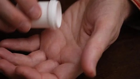 Person pouring red pills into hand for daily medication. closeup. Video stock 320208853