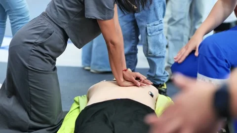 Person practicing life-saving techniques on a CPR mannequin in an educational Stock Footage 325044317