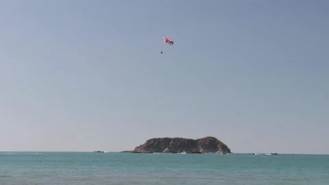 Person practicing parasailing over Manuel Antonio beach, Costa Rica Stock Footage 225644471