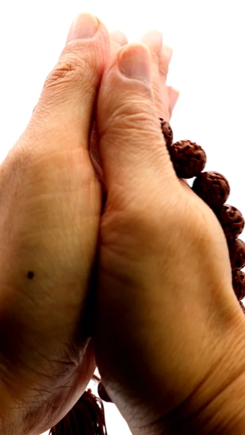 A person praying with prayer beads Stockbeeldmateriaal 336080668
