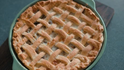 A person prepares a pie by hand, creating a lattice crust over the filling. Stock Footage 339094735