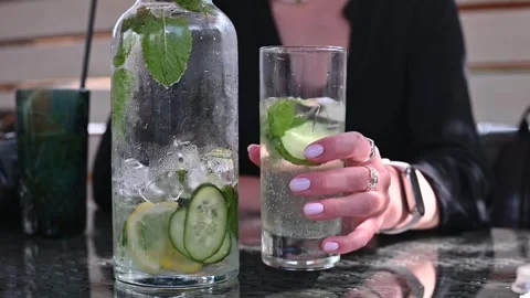 A person prepares a refreshing drink with cucumber and lemon in a glass. Stock Footage 337101137