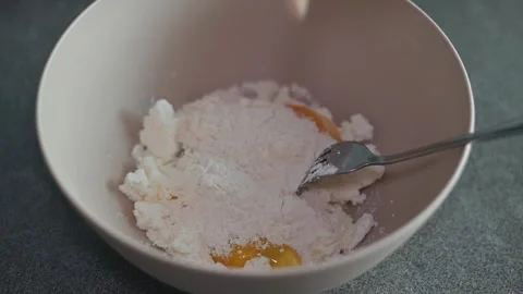 A person is preparing to bake by mixing flour and eggs in a bowl cottage cheese Stock Footage 339096272