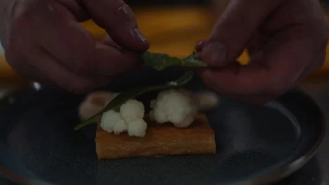 A person is preparing a dish with a piece of broccoli on top Stock Footage 295995398