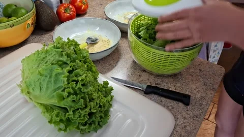 Person Preparing Fresh Lettuce Using a Salad Spinner in Kitchen Stock Footage 342405757