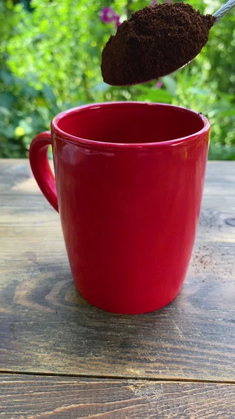 Person preparing hot brew, spooning coffee grounds into ceramic mug. Stock Footage 340514979