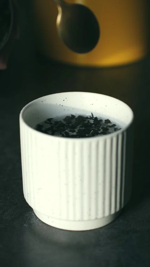 Person preparing loose leaf black tea in white ceramic cup Stock Footage 323718244