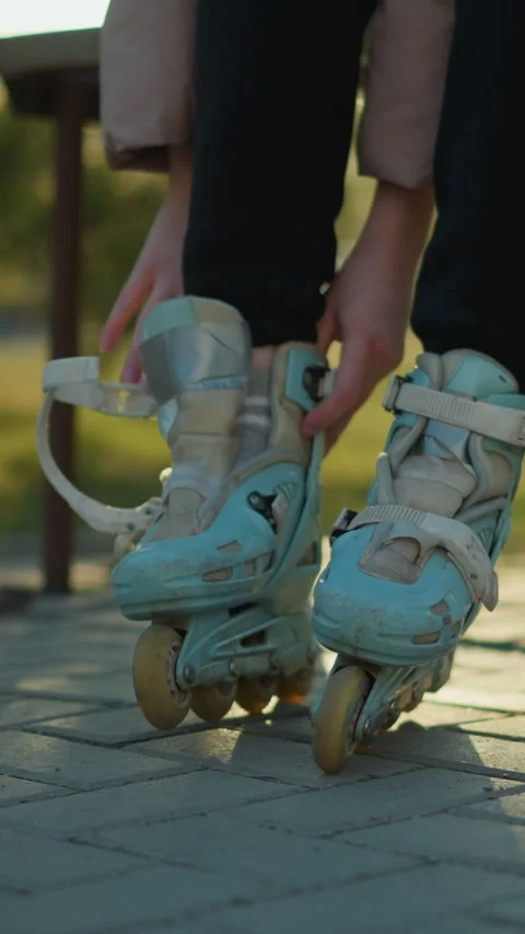 Person Preparing to Put on Rollerblade in Sunlit Park Setting Stock Footage 310492549
