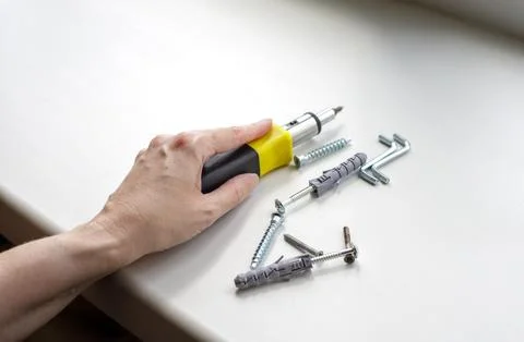 Person preparing tools for fixing plastic window frame hardware indoors. Hand Stock Photos