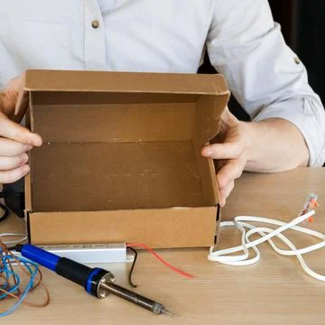 Person presenting empty cardboard box on work surface Stock Photos