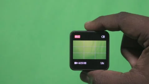 Person Presenting a Tiny Electronic Gadget on Green Background. Stock Footage 342277867