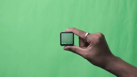 Person Presenting a Tiny Electronic Gadget on Green Background. Stock Footage 342289137