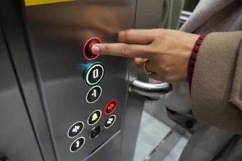 Person presses button in elevator at busy location Foto stock