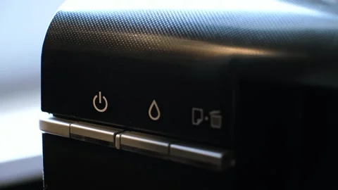 The person presses a button turning on the printer. The device has a green Stock Footage 314622018