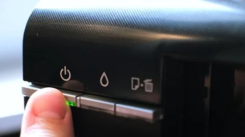 The person presses a button turning on the printer. The device has a green 库存照片